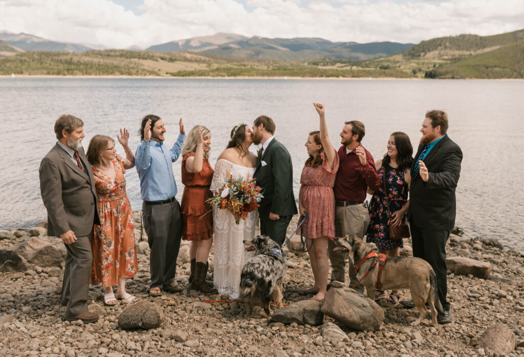 Guests cheer for a bride and groom as they kiss in front of mountains and Dillon Reservoir near Breckenridge, Colorado 
