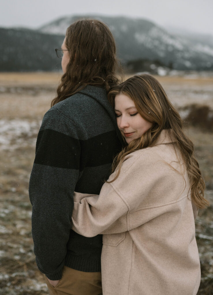 A couple poses for their engagement photos in Rocky Mountain National Park near Estes Park, Colorado. Find out what to wear for winter engagement photos in Colorado.
