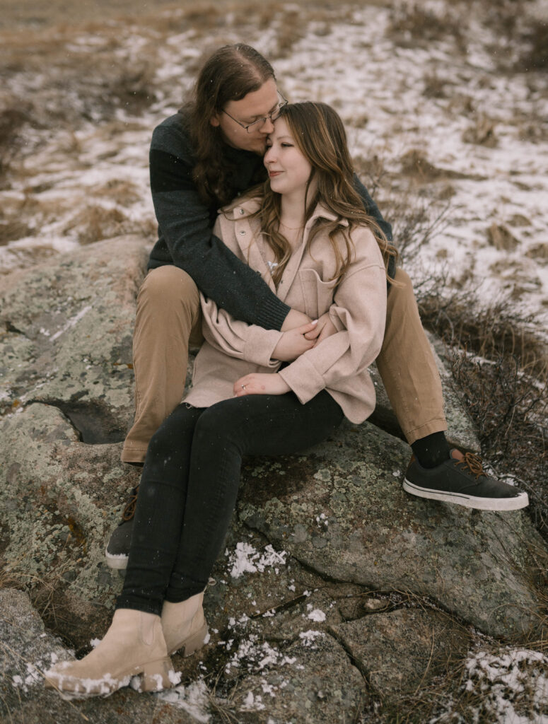 A couple poses for their engagement photos in Rocky Mountain National Park near Estes Park, Colorado. Find out what to wear for winter engagement photos near Denver, Colorado.