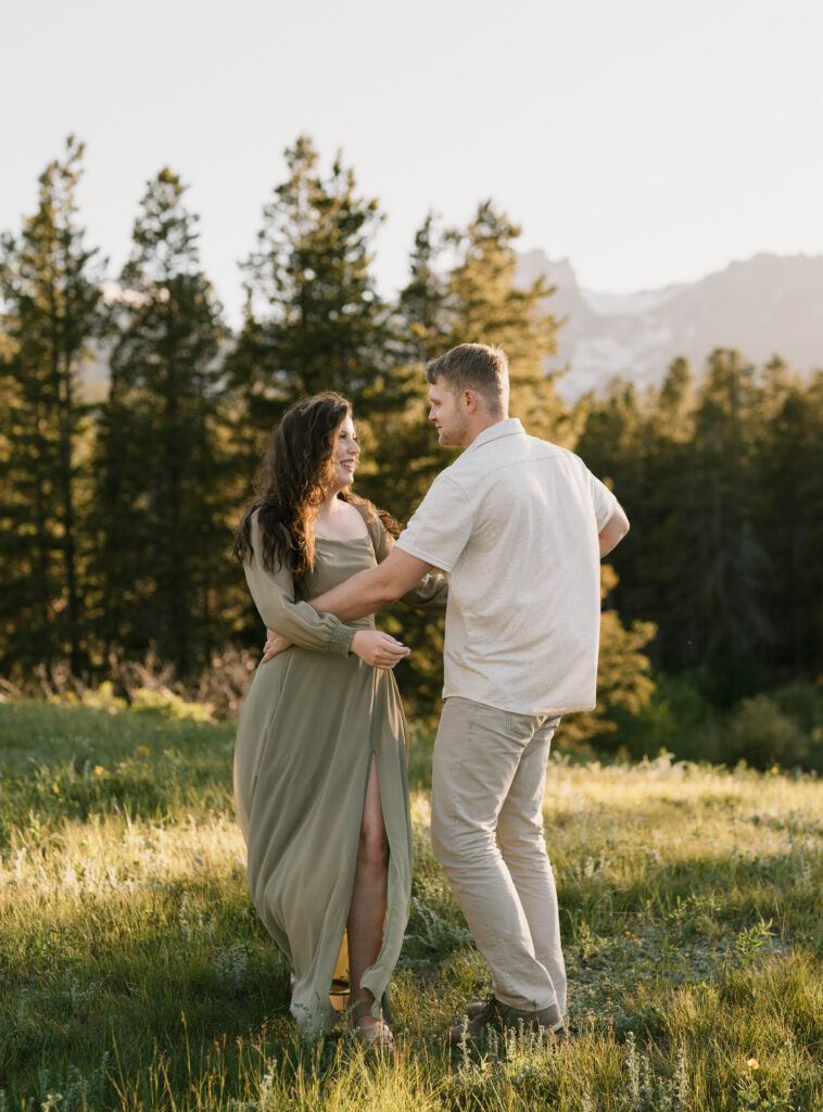A couple dances at Sprague Lake for their engagement photos in Estes Park. Learn how to choose the perfect outfit for engagement photos near Denver, Colorado.