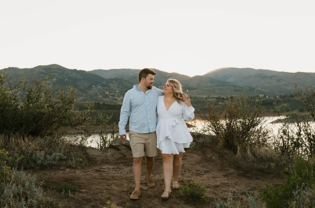 A couple walks together at Horsetooth Reservoir for their engagement photos in Fort Collins, Colorado. Learn how to choose the perfect clothes for engagement photos near Denver, Colorado.