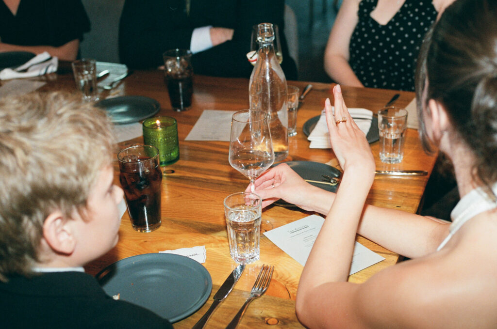 A candid dinner party photo captured in a documentary style on 35mm film at an intimate wedding reception in NYC