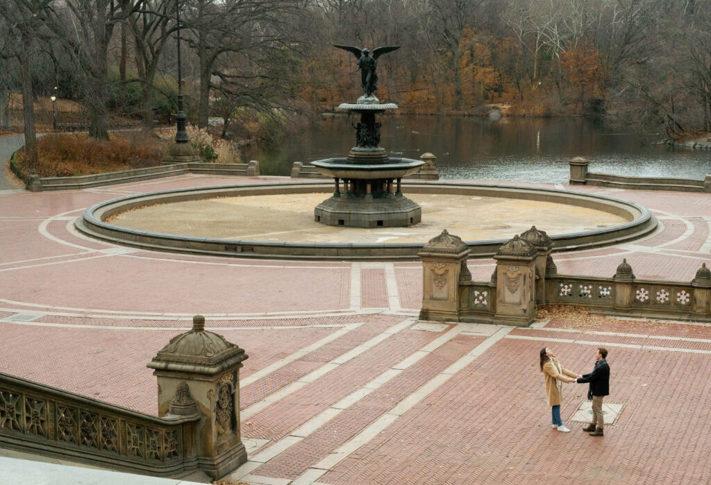 A candid moment with a couple dancing during their engagement photos in Central Park outside Bethesda fountain in the winter, showcasing how intimate New York City can feel for couples photos. 