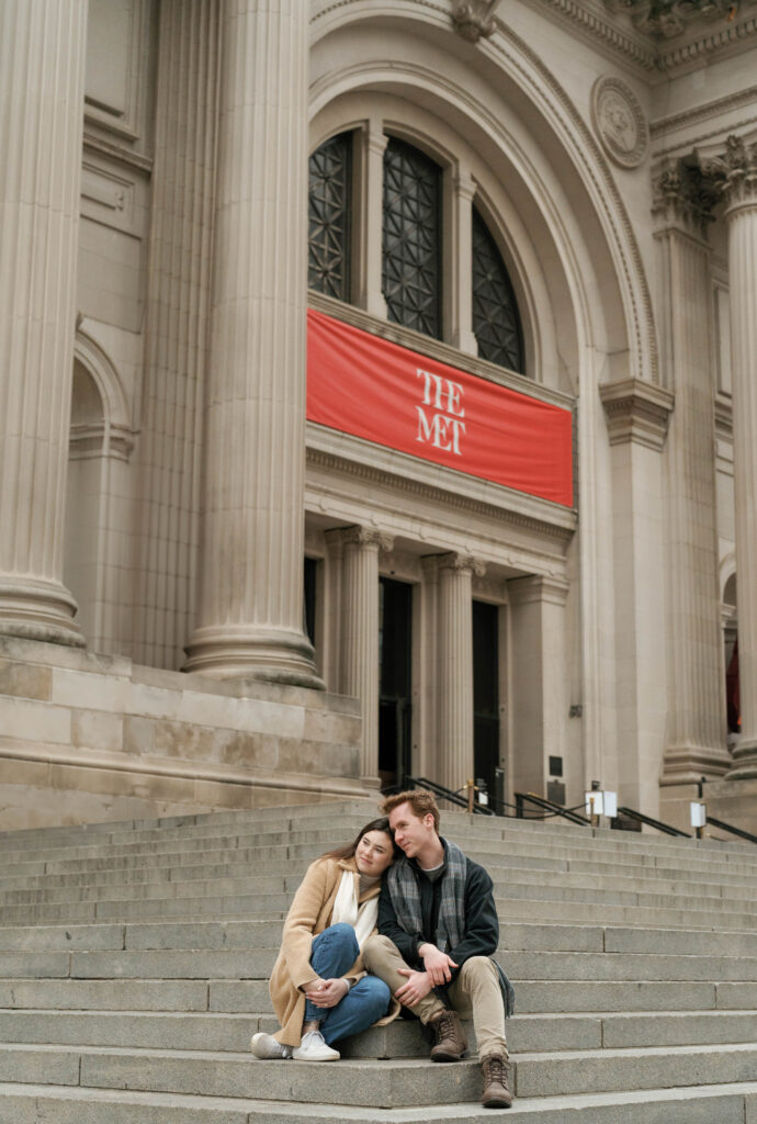 A couple sits together The Met Museum. Discover romantic photos from an engagement session in New York City.
