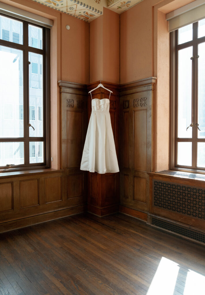 An elegant and timeless wedding dress hanging inside at a downtown Dallas, Texas wedding at the 400 N Ervay wedding venue. Discover candid, editorial, and documentary wedding photos on digital and film. 