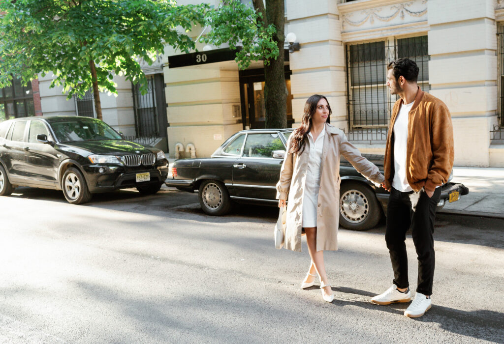 Engaged couple posing in front of a vintage car in the West Village in NYC. Discover timeless engagement photography in New York City. 