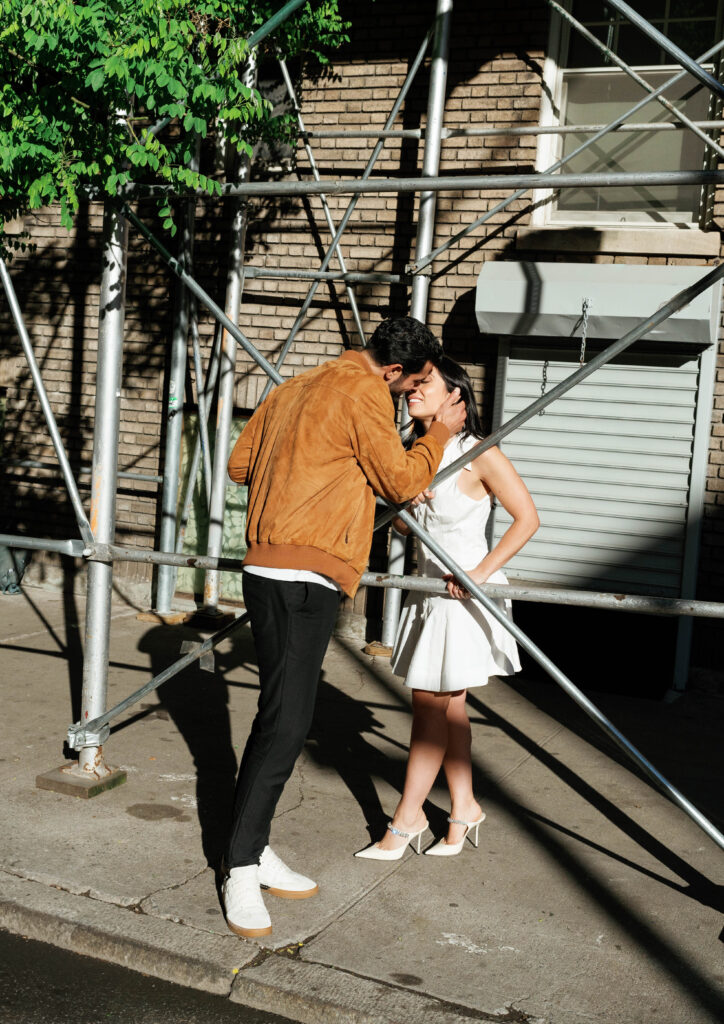 Romantic kiss between engaged couple in front of iconic Greenwich Village building. Discover intimate and documentary engagement photos in New York City. 