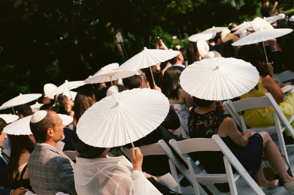 A documentary photo of wedding guests with parasols. Discover candid film wedding photography in New York City.