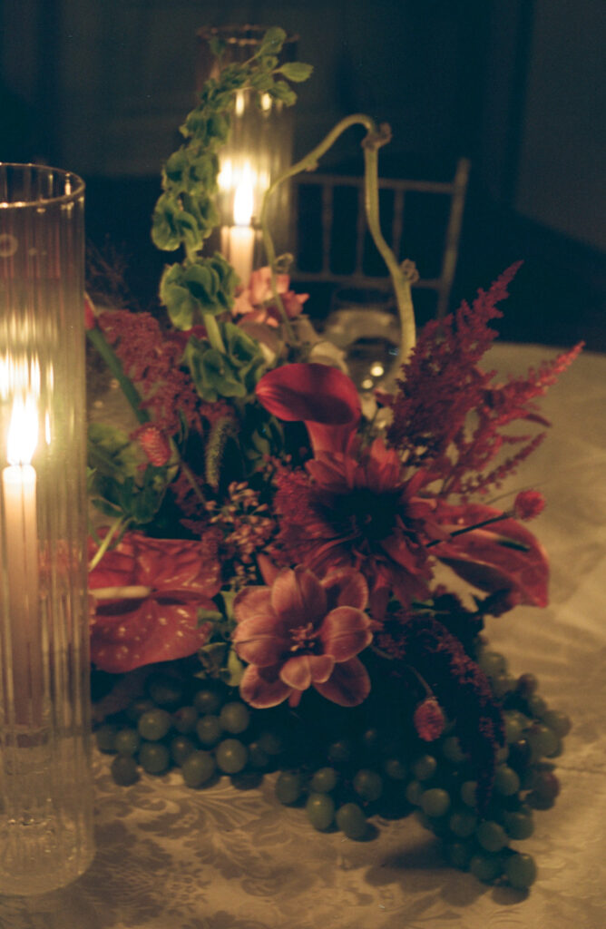 A photo of a table floral arrangement with ambient candlelight on 35mm film. Discover editorial film wedding photography in New York City.