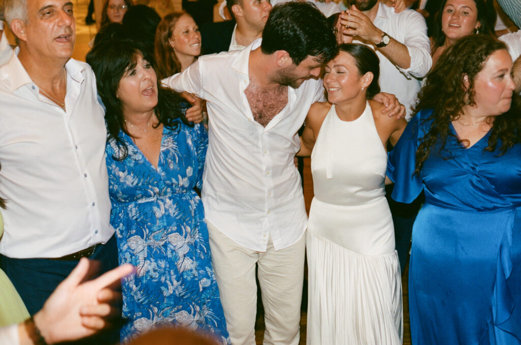 A candid photo of a bride and groom dancing with guests on their wedding day. Discover documentary film wedding photography in New York City.