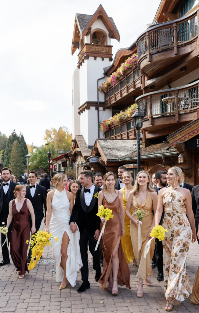 A wedding party poses for fall wedding in Vail Village. Discover luxury documentary wedding photography in Colorado and beyond.  