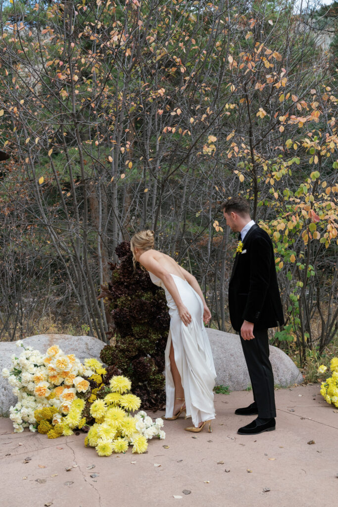 A couple poses near their fall wedding florals in Vail. Discover yellow wedding inspiration and luxury wedding photography in Colorado and beyond.  