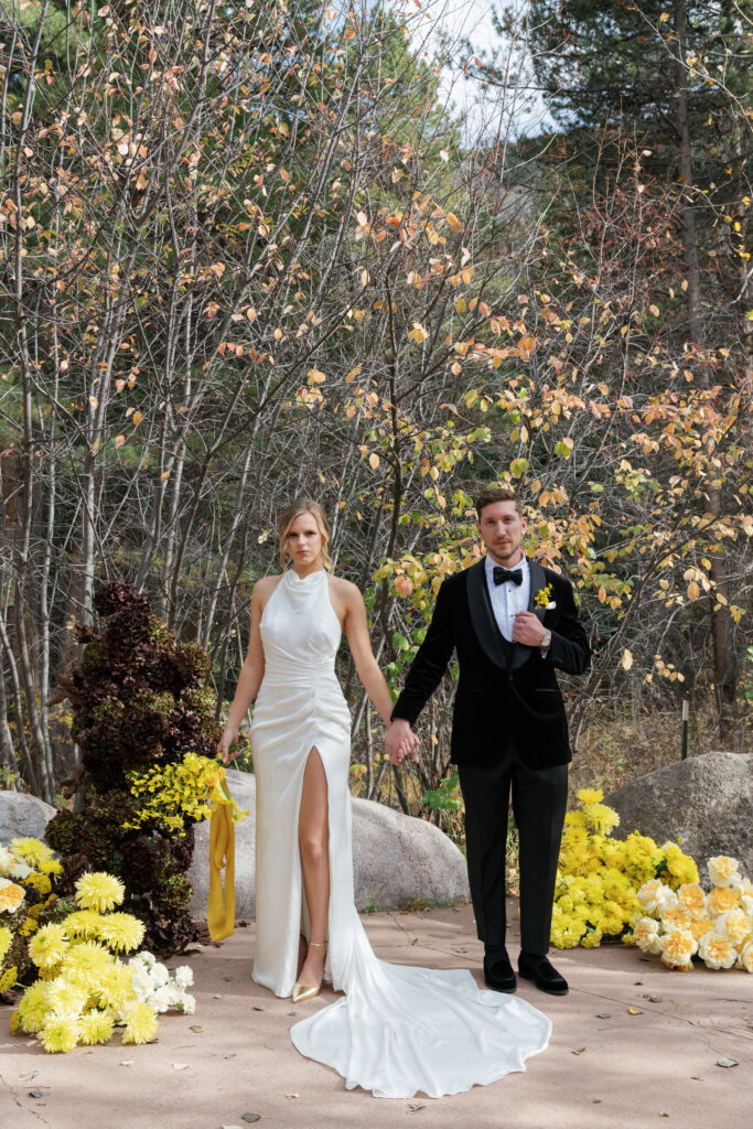 A couple poses near their fall wedding florals in Vail. Discover yellow wedding inspiration and luxury wedding photography in Colorado and beyond.  